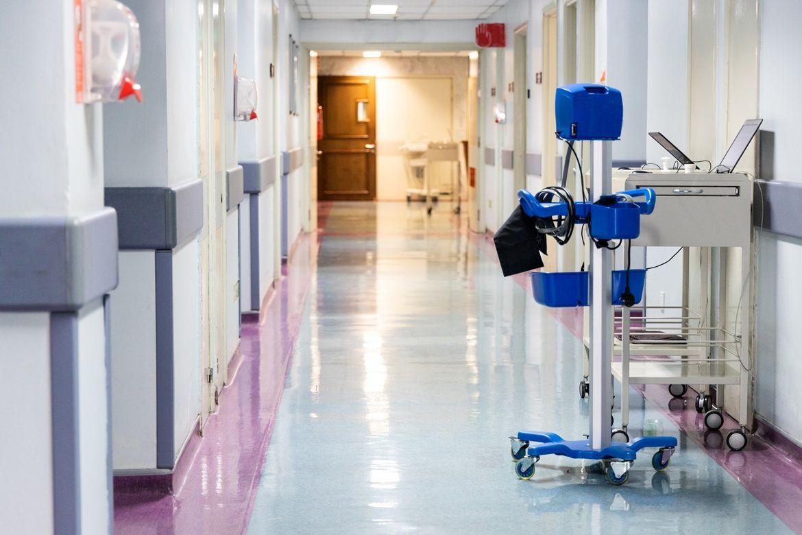 szafka na kółkach z komputerami i wózek medyczny stojące na szpitalnym korytarzu