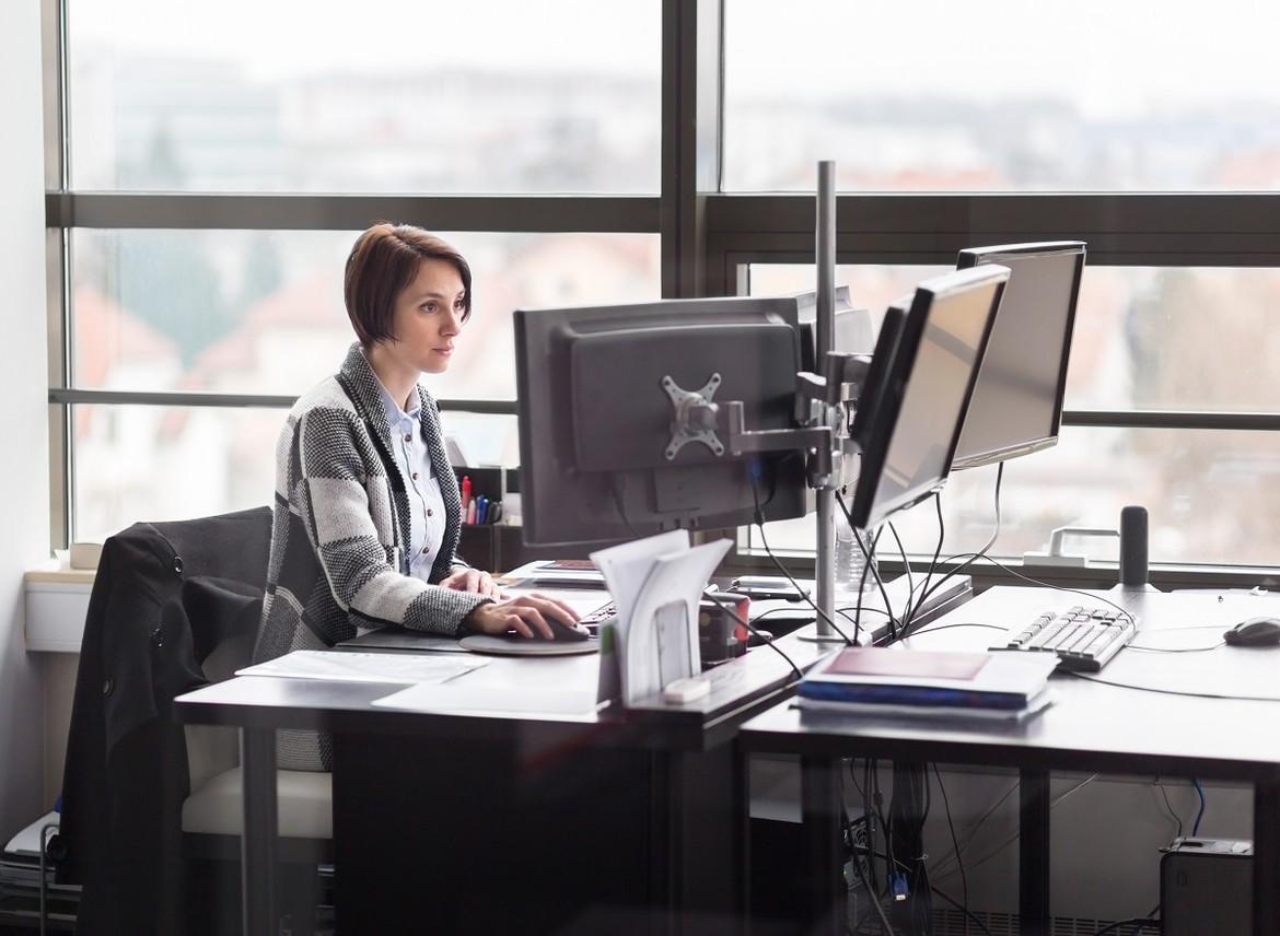 kobieta siedząca przy biurku i pracująca przy komputerze