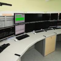 stanowisko operatorskie z trzynastoma monitorami, pięcioma klawiaturami koloru czarnego, pięcioma myszkami biało-czarnymi i jedną czarną
